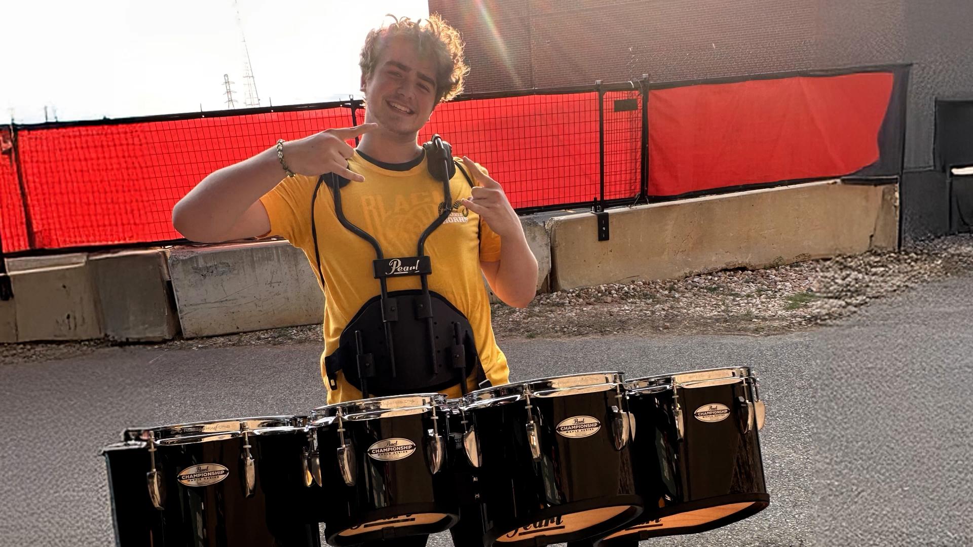 VCU student smiles while wearing a set of four drums