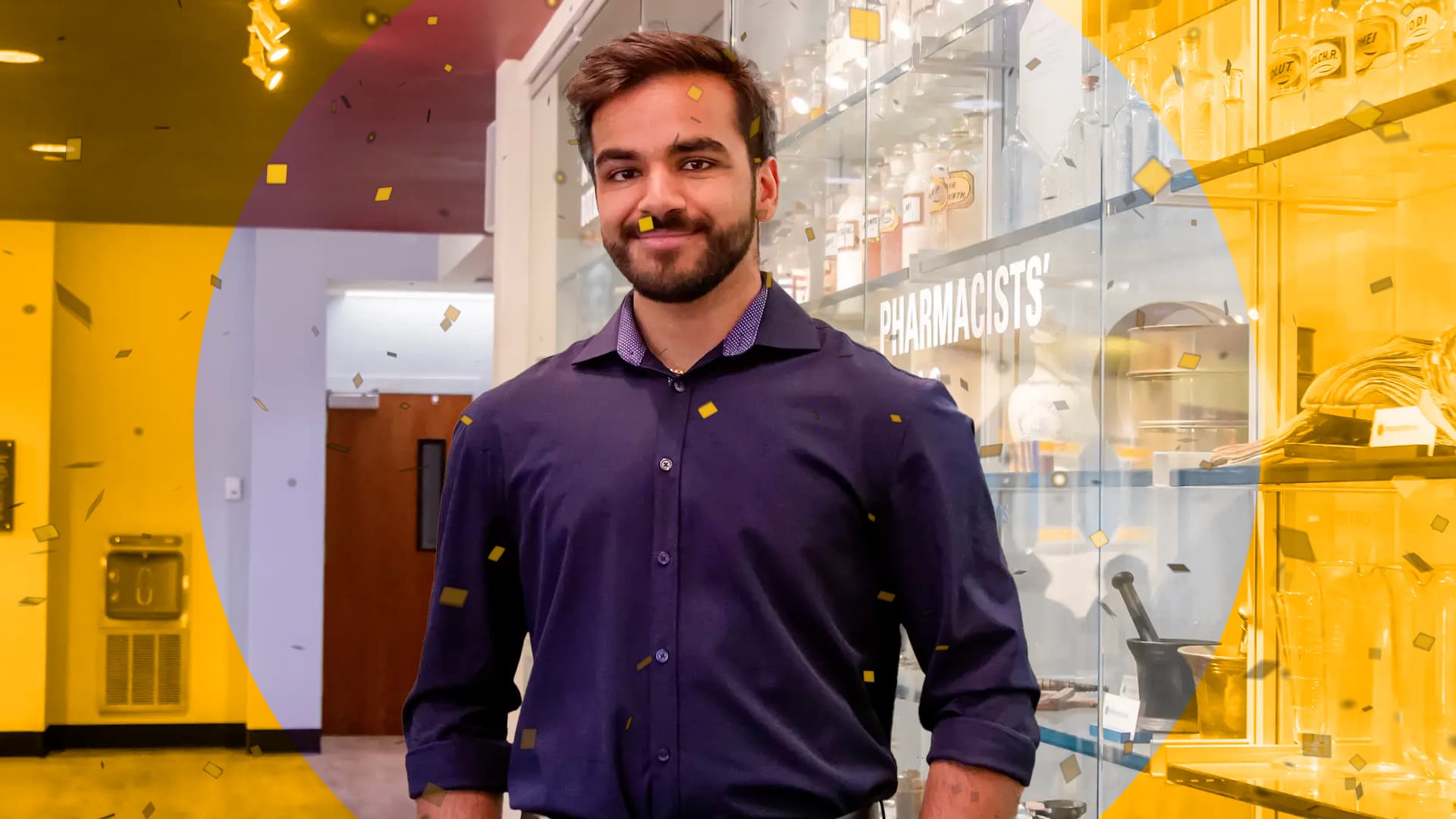 Student stands in building smiling with yellow confetti around 