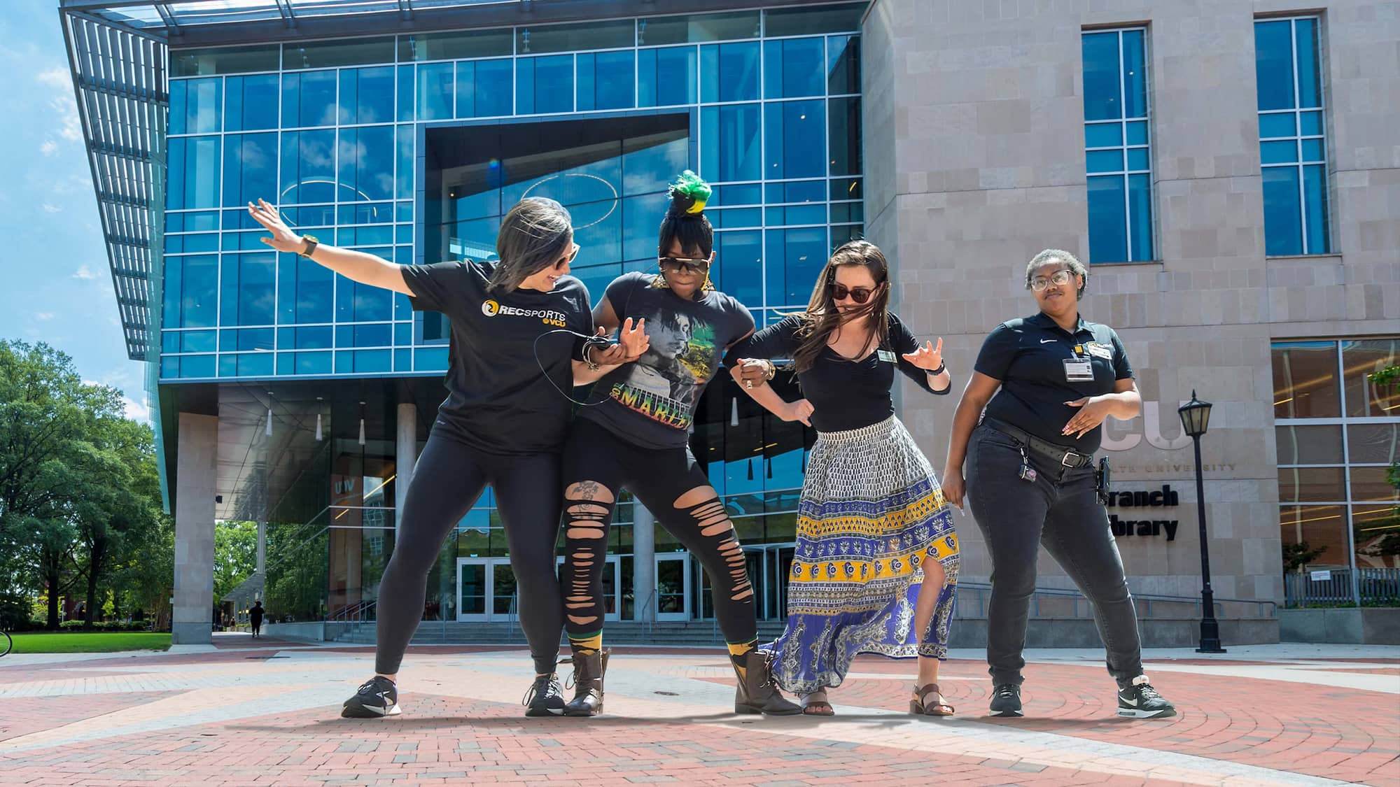 Four female VCU students standing arm-in-arm in from of Cabell Library