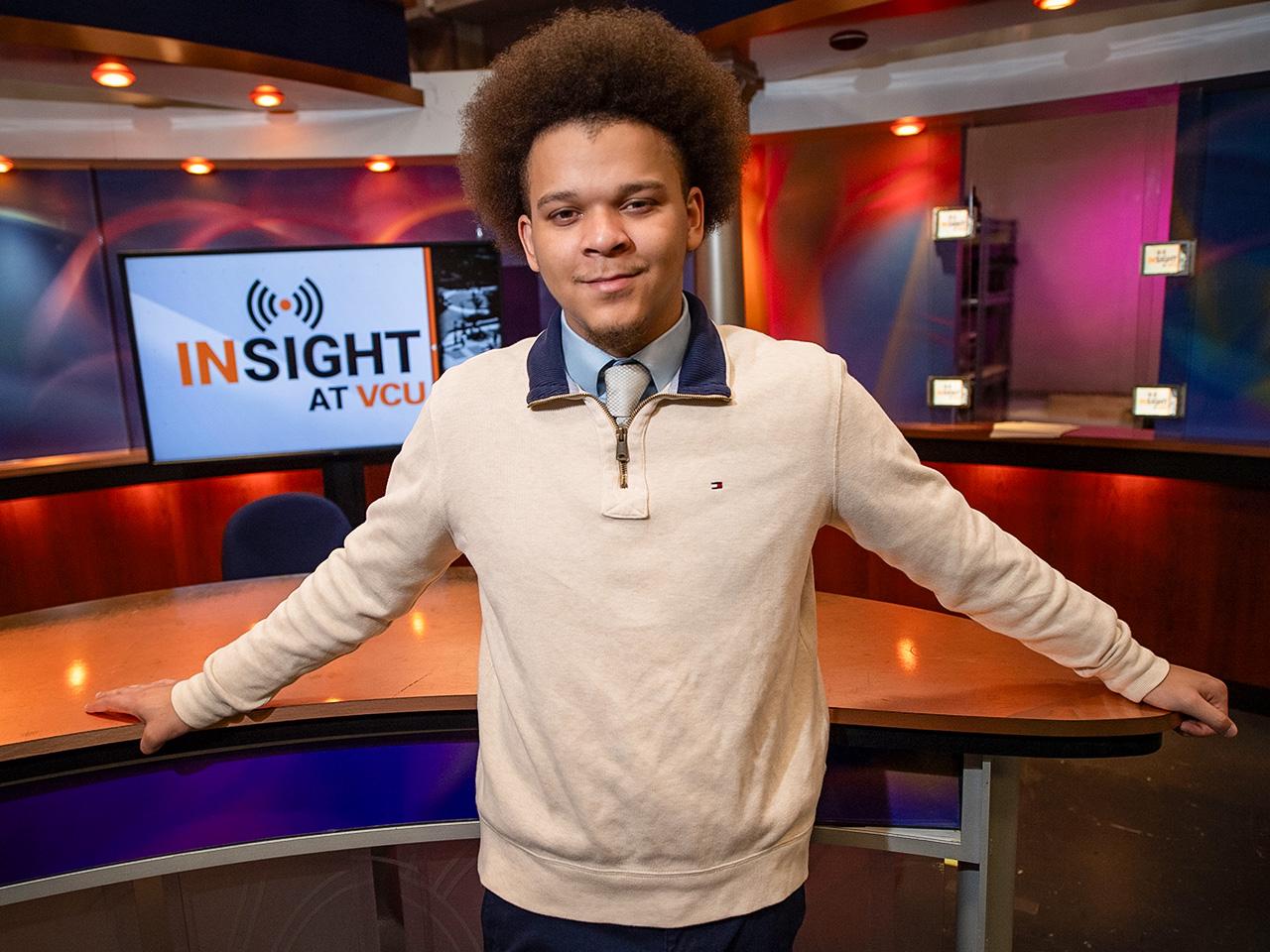 Kyler Gilliam standing in newsroom with tv displays in the background