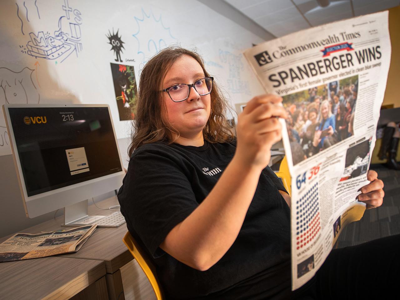 Sarah Hagen holding a newspaper highlighting the winner of a gubernatorial election