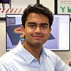 Nihal Patel sitting at a work desk with a computer display and 3d printers