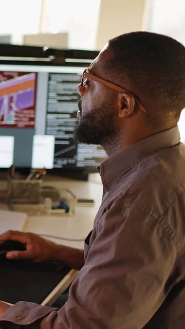 An engineer analyzes technical designs on multiple monitors in a modern workspace. Advance your career—learn more about our Engineering Management Master’s Program!
