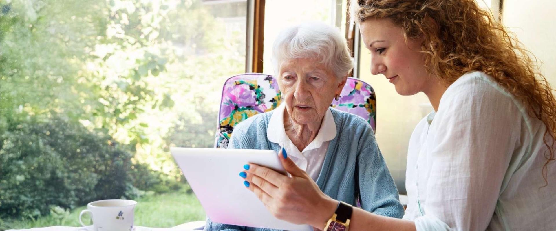 Professional, sitting beside their patient, reviewing the contents of a tablet together.