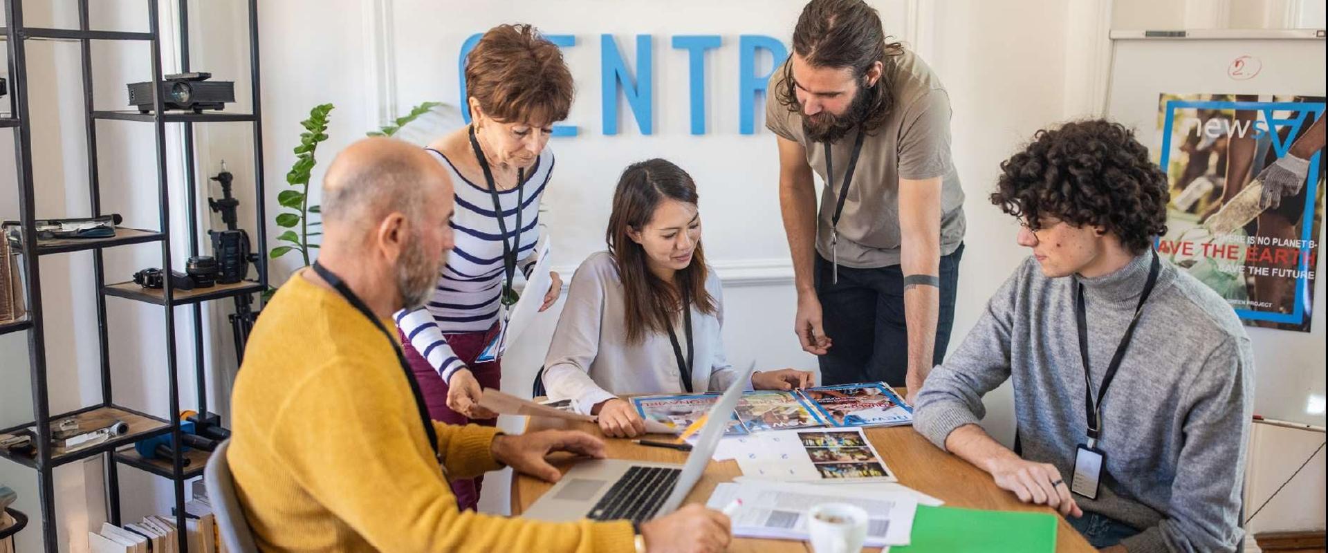 Colleagues gathered around a meeting table, discussing their next media campaign.