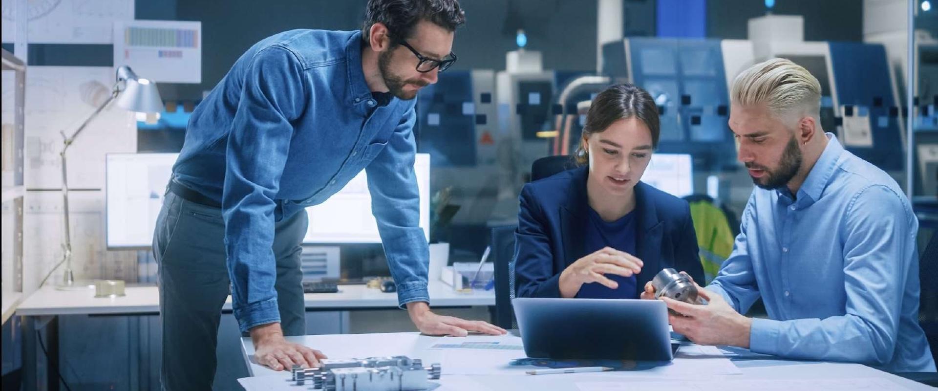 Colleagues sitting at a table, reviewing the contents of a tablet.