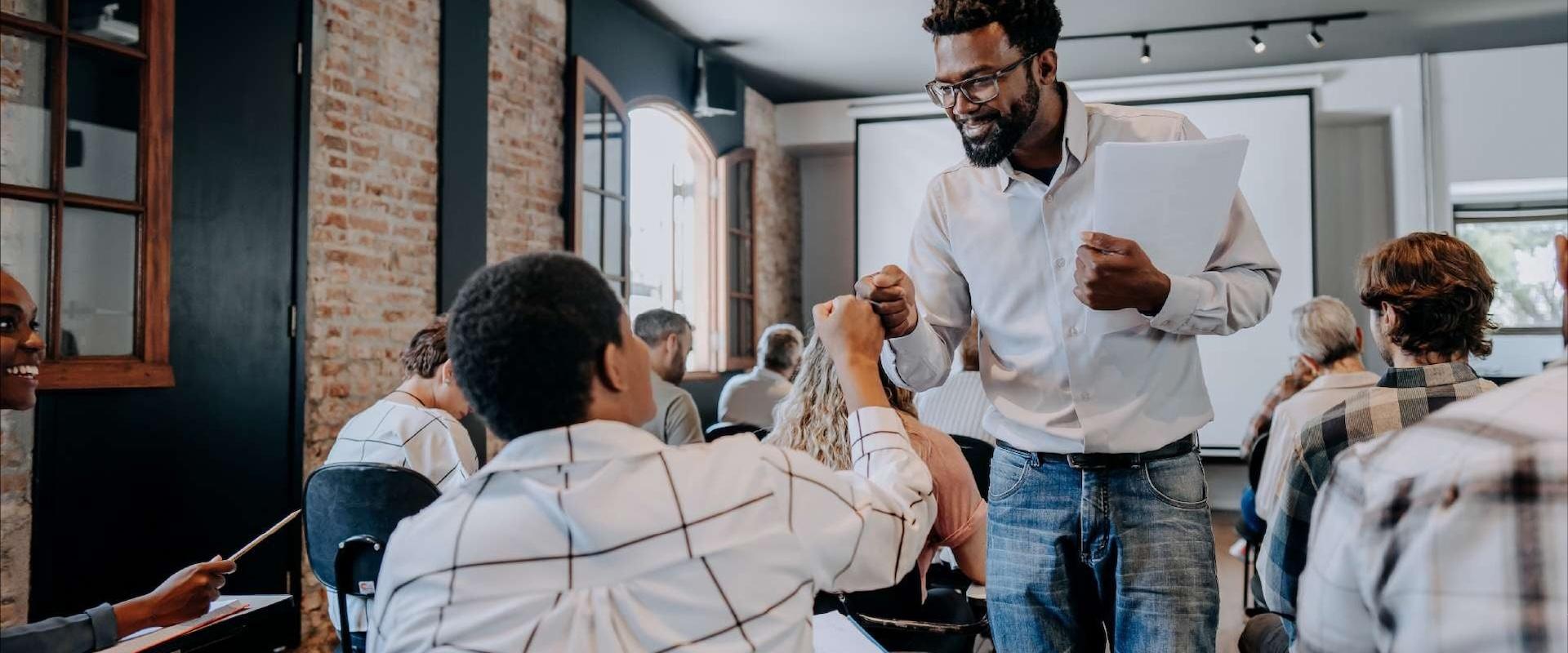 Smiling educator fist bumps a teenage student.