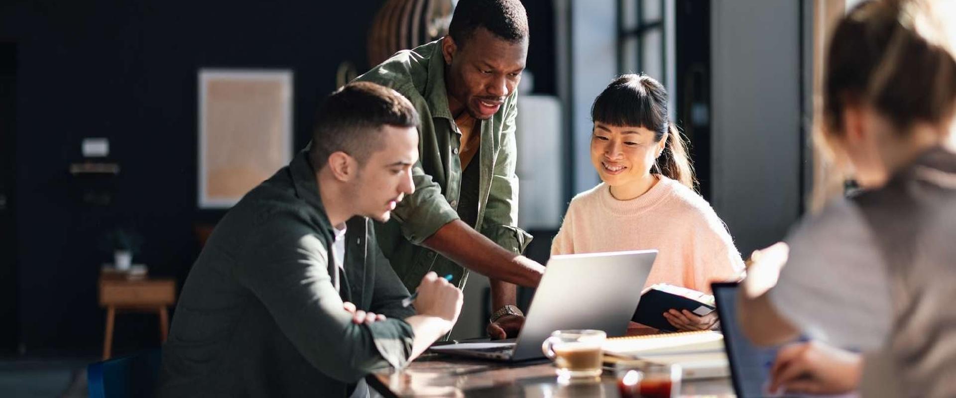 Smiling colleagues gathered together, discussing the content on a tablet.