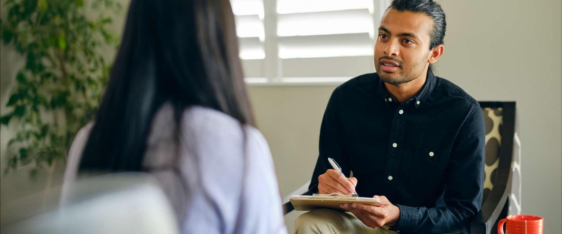 Specialist holding clipboard listening attentively to client during session.