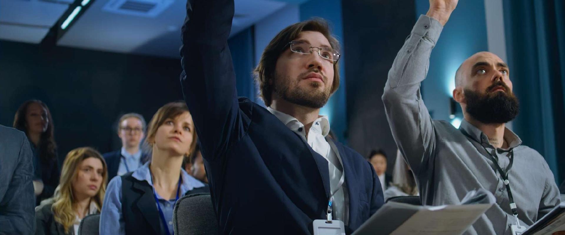 A group of media industry professionals raising their hands to ask a question in a crowd