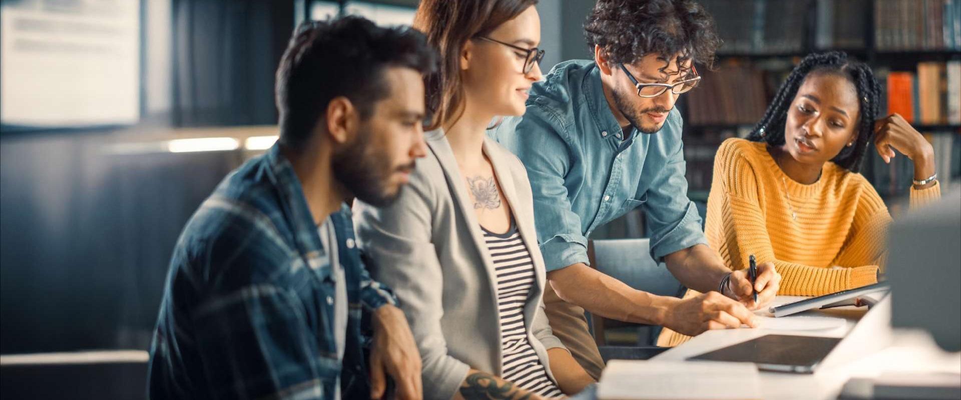 Group of students working together at a table getting advice from a faculty member
