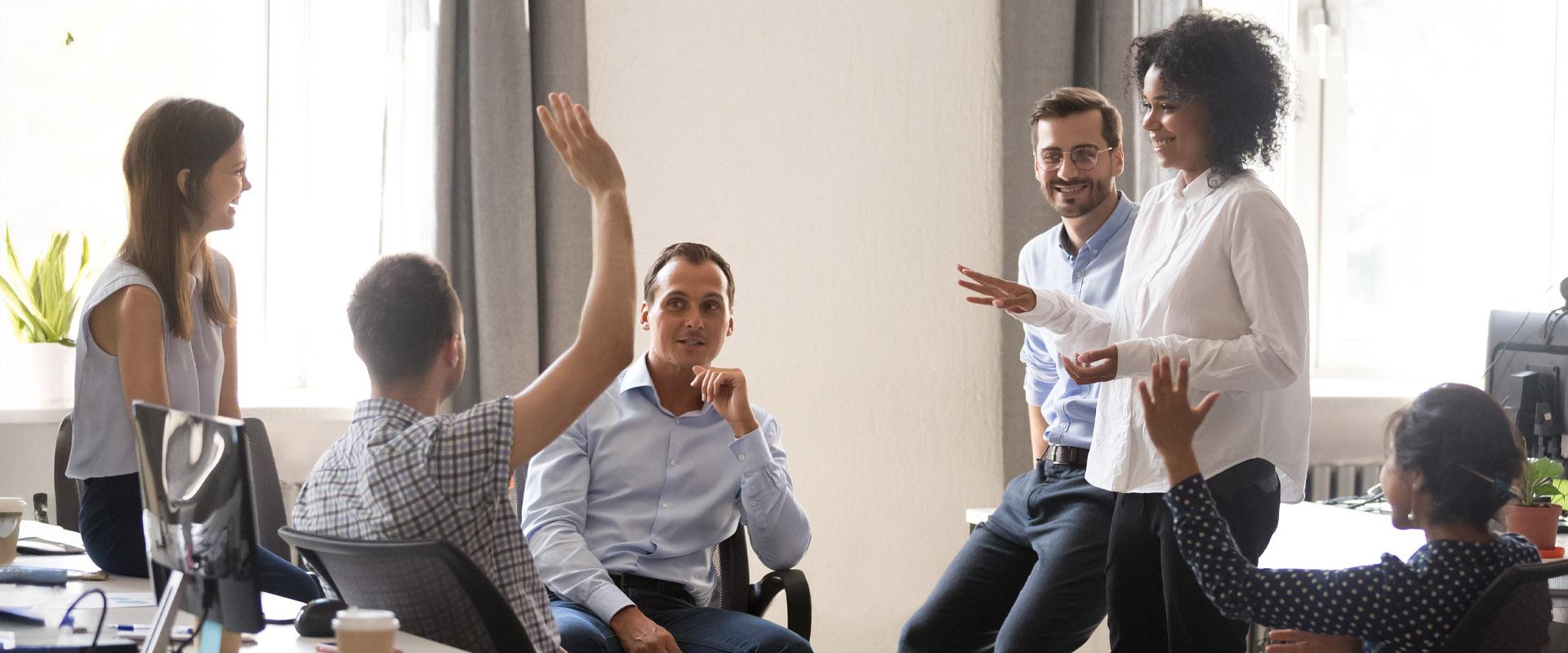 A professional fielding questions from their smiling colleagues.