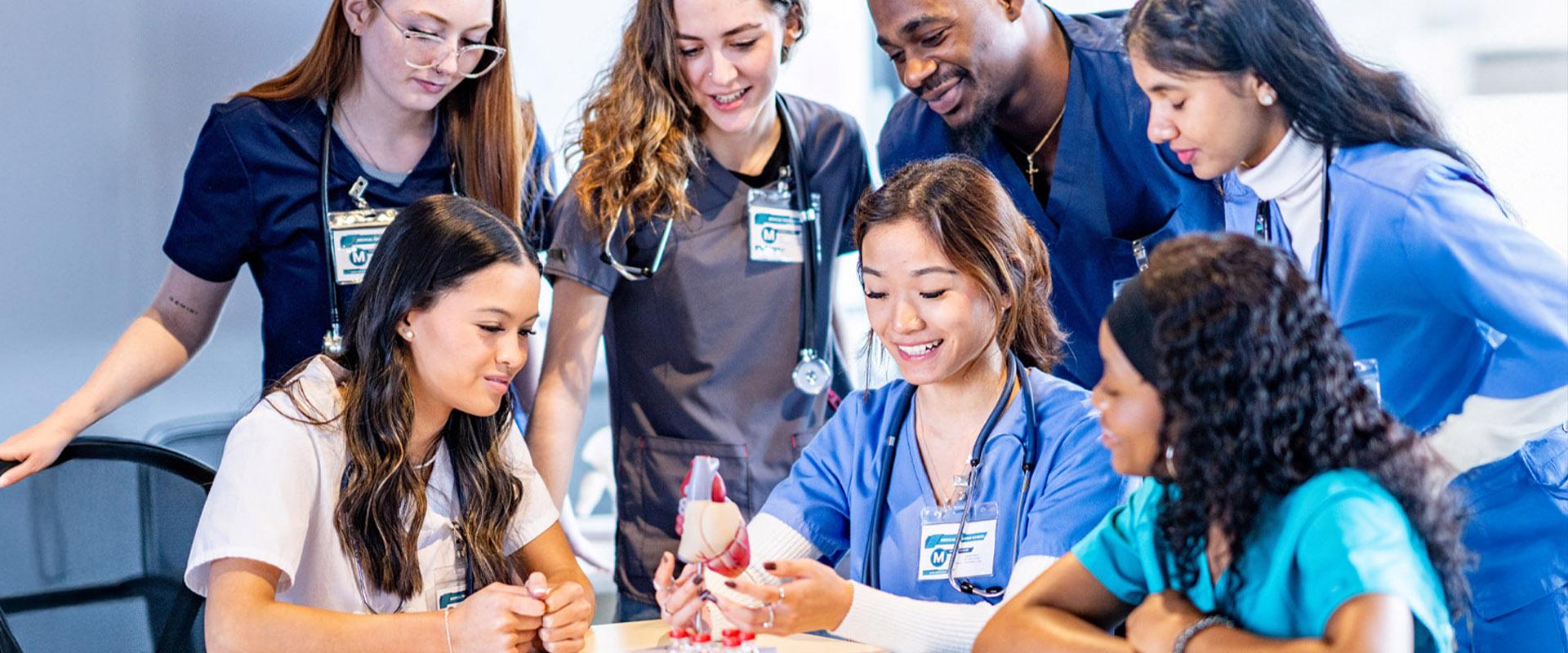 A group of nurses gathered to watch an instructor explain a concept.