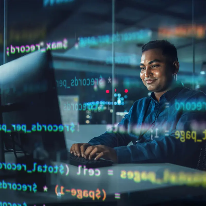 Professional looking contently at their computer monitor. An translucent overlay of code is visible above and below their head.