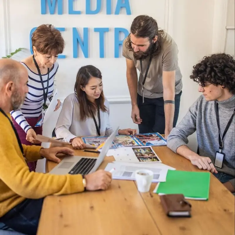 Colleagues gathered around a meeting table, discussing their next media campaign.