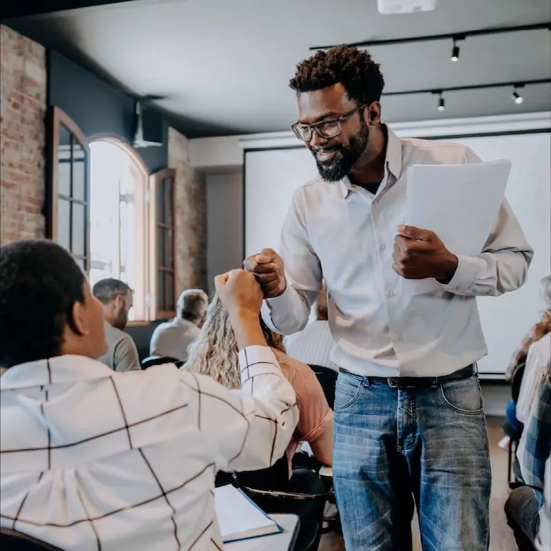 Smiling educator fist bumps a teenage student.
