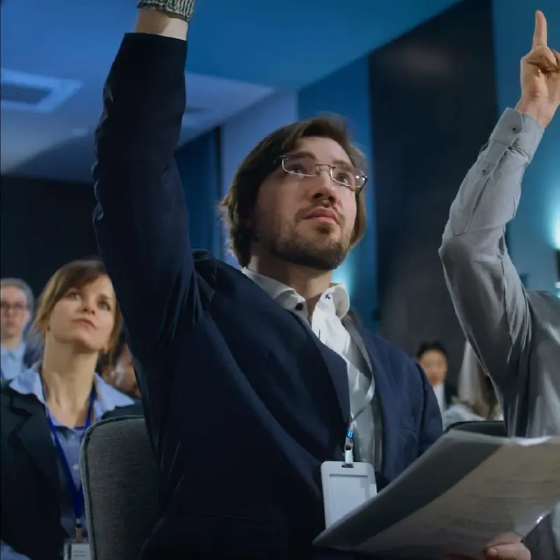 A group of media industry professionals raising their hands to ask a question in a crowd
