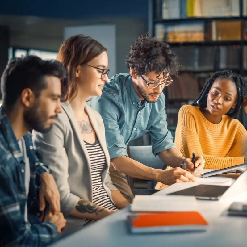 Group of students working together at a table getting advice from a faculty member