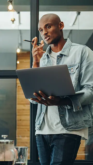 A diverse group of five people sitting around a small table conversing about a pie chart in a presentation on a laptop