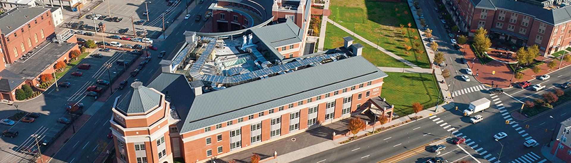 Aerial view of VCU’s Monroe Park Campus with academic buildings, open green space and the Richmond skyline in the background.