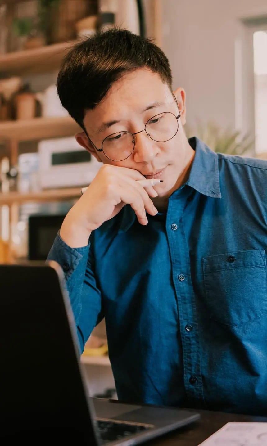 Person wearing glasses holding a pencil with a look of contemplation